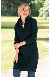 Dunkelblaues Strickkleid mit hohem Stehkragen, lange Ärmel, knielang, schmal geschnitten, getragen von lächelnder stehender Frau vor grüner Außenkulisse