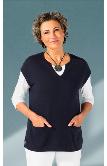 Damenweste dunkelblau, ärmellos, V-Ausschnitt, zwei aufgesetzte Taschen, getragen von stehender Frau mit weißen Dreiviertelarmshirt und weißer Hose