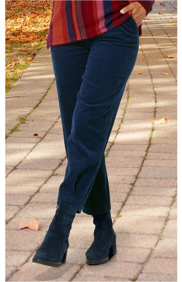 Dunkelblaue Hose mit geradem Schnitt, ohne Muster, getragen von stehender Person, sichtbar untere Körperhälfte, kombiniert mit schwarzen Stiefeletten