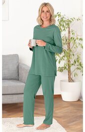 Damen-Pyjama in grün, langärmeliges Oberteil mit Rundhalsausschnitt, gerade geschnittene Hose, getragen von stehender Frau, barfuß, ruhige Pose, ohne Muster, schlichtes Design