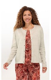 Beige langärmelige Strickjacke, rundhals, durchgehende Knopfleiste, getragen von lächelnder stehender Frau mit offenen Haaren, darunter rot gemustertes Kleid mit Kreis- und Punktmustern