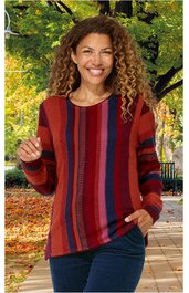 Pullover in Rostrot mit verschiedenen breiten senkrechten Streifen in Dunkelrot, Blau und Schwarz, Rundhalsausschnitt, lange Ärmel, getragen von lächelnder Frau mit lockigen Haaren, stehende Pose, locker geschnitten