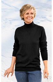 Schwarzer Rollkragenpullover, langärmlig, gerade geschnitten, getragen von lächelnder stehender Frau, kombiniert mit blauen Jeans