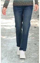 Person geht auf einem Weg, trägt blaue Jeans und helle Schuhe