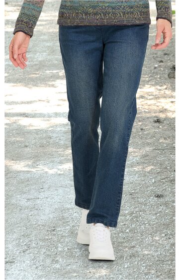 Person geht auf einem Weg, trägt blaue Jeans und helle Schuhe