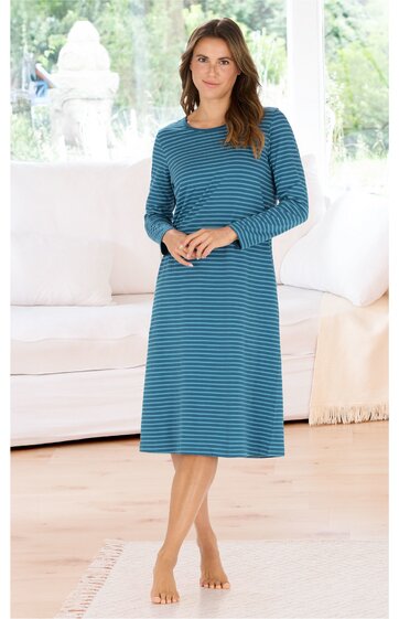 Knielanges, blau gestreiftes Nachthemd mit langen Ärmeln, Rundhalsausschnitt, gerade geschnitten, getragen von nackten, stehenden Frau in Innenraum