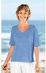 Hellblaues Kurzarmshirt mit V-Ausschnitt, gerade geschnitten, seitliche Schlitze am Saum, getragen von lächelnder Frau stehend vor Meereskulisse