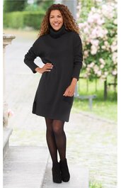 Schwarzes Strickkleid mit Rollkragen, langärmelig, knielang, gerade geschnitten, getragen von stehender Frau mit rechten Hand in der Hüfte, schwarzer Strumpfhose, schwarzer Stiefeletten