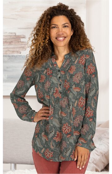 Langärmlige Bluse in dunklem Olivgrün mit floralen rosa Mustern, durchgehende Knopfleiste, Stehkragen, gerade geschnitten, getragen von stehender Frau mit einer Hand in der Hüfte