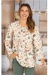 Locker geschnittene, cremeweiße Bluse mit buntem Blumenmuster, langer Ärmel, Rundhalsausschnitt mit kleiner Knopfleiste vorne, getragen von lächelnder, stehender Frau mit offener Haltung