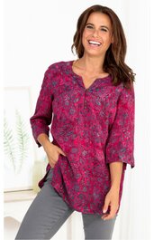 Rosa Bluse mit floralen Muster in dunklen Blautönen, V-Ausschnitt mit Knopfleiste, lange Ärmel, lockerer Schnitt, getragen von lächelnder stehender Frau mit dunklen Haaren, seitliche Taschen