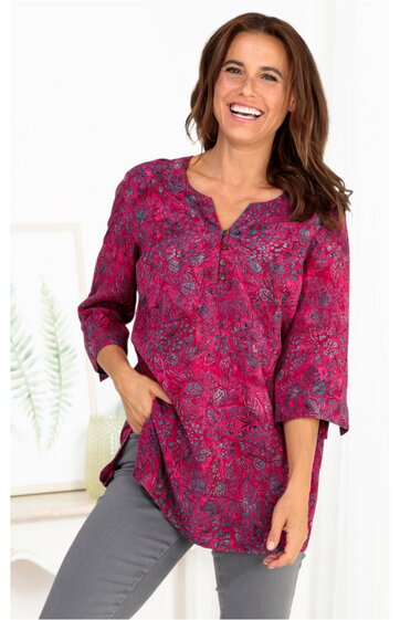 Rosa Bluse mit floralen Muster in dunklen Blautönen, V-Ausschnitt mit Knopfleiste, lange Ärmel, lockerer Schnitt, getragen von lächelnder stehender Frau mit dunklen Haaren, seitliche Taschen