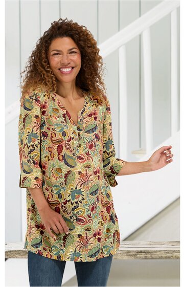 Tunika in hellgelb mit großflächigem floralen Muster in Rot, Blau, Grün, V-Ausschnitt mit kurzen Knopfleisten, 3/4-Ärmel mit Riegel, locker geschnitten, getragen von lächelnder stehender Frau