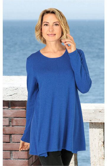 Blauer Pullover mit rundem Ausschnitt, langärmlig, locker geschnitten, getragen von stehender Person vor Meereshintergrund