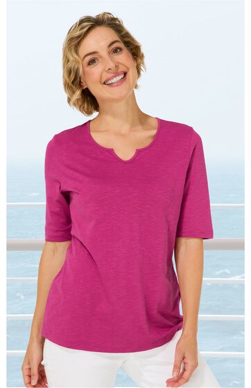 Kurzarmliges T-Shirt in dunklem Rosa ohne Muster, Rundhalsausschnitt mit kleinem V-Detail, gerade geschnitten, getragen von stehender Frau mit leichten Wellen im schulterlangen Haar