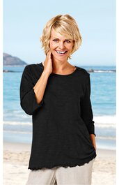 Schwarzer Damenpullover mit rundem Ausschnitt, dreiviertellangen Ärmeln, gewelltem Saum, gerade geschnitten, getragen von lächelnder Frau vor Strandhintergrund