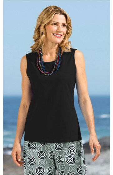 Ärmelloses schwarzes Top mit rundem Halsausschnitt, getragen von lächelnder stehender Frau, kombiniert mit weißen Shorts mit schwarzem Spiralmuster, mehrreihige bunte Ketten als Accessoire