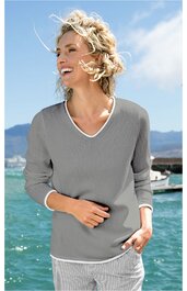 Langarmshirt in hellgrau mit weißem V-Ausschnitt und weißen Ärmelbündchen, gerade geschnitten, getragen von stehender lachender Frau vor Meer und blauem Himmel