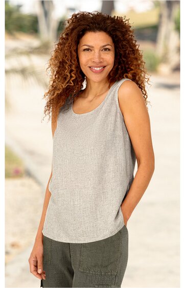 Ärmelloses, hellgraues Top mit Rundhalsausschnitt, gerade geschnitten, getragen von stehender Frau mit lockigen braunen Haaren, grüne Hose, rechte Hand in Hosentasche