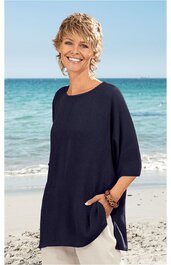 Dunkelblaues, locker geschnittenes Langarmshirt ohne Muster, rundhals, seitliche Taschen, getragen von lächelnder Frau stehend am Strand vor Meer