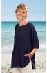 Dunkelblaues, locker geschnittenes Langarmshirt ohne Muster, rundhals, seitliche Taschen, getragen von lächelnder Frau stehend am Strand vor Meer