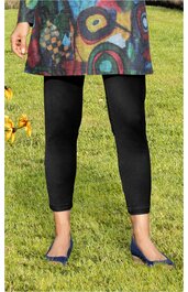 Schwarze Leggings, knöchellang, blickdicht, getragen von stehender Person, blaue spitze Ballerinas, bunter Kurzmantel mit abstraktem Muster, Grasfläche im Hintergrund