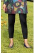 Schwarze Leggings, knöchellang, blickdicht, getragen von stehender Person, blaue spitze Ballerinas, bunter Kurzmantel mit abstraktem Muster, Grasfläche im Hintergrund