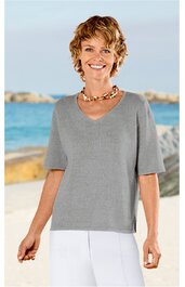 Hellgraues Kurzarmshirt mit V-Ausschnitt, lockere Passform, getragen von stehender lächelnder Frau vor Strandkulisse, schlicht ohne Muster oder Verzierungen