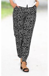 Schwarze Hose mit weißem, geschwungenem Muster, gerade geschnitten, seitliche Eingrifftaschen, getragen von stehender Person, kombiniert mit schwarzen Sandalen mit Absatz