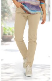 Helle, beige Hose mit schmal zulaufendem Bein, getragen von stehender Person, mit seitlichen Taschen, kombiniert mit weißen Schnürschuhen und gemustertem, locker sitzendem Oberteil