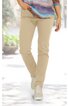 Helle, beige Hose mit schmal zulaufendem Bein, getragen von stehender Person, mit seitlichen Taschen, kombiniert mit weißen Schnürschuhen und gemustertem, locker sitzendem Oberteil