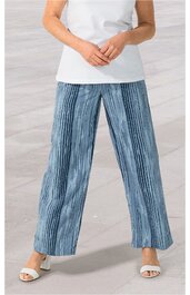 Weitgeschnittene Hose in Blau mit vertikalen weißen Streifen, hoher Bund, getragen von stehender Person mit weißem Oberteil und weißen Sandalen