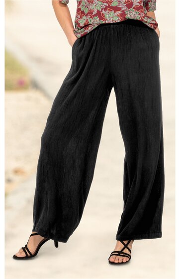 Schwarze weite Hose mit elastischem Bund, geradem Schnitt, getragen von Person im Stehen, kombiniert mit schwarzen offenen Sandalen mit hohen Absätzen