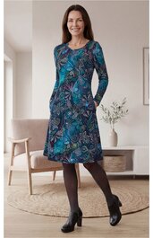 Kleid, dunkelblau mit floralem Muster in Blau- und Türkistönen, langärmlig, knielang, rundhals, ausgestellter Rock, getragen von stehender Frau mit geschlossenen Beinen, seitliche Taschen