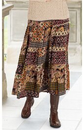 Maxirock mit buntem Patchwork-Muster in Braun-, Rot- und Beigetönen, elastischer Bund, weite Form, getragen von stehender Person mit beigefarbenem Strickpullover und braunen Stiefeln