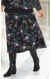 Schwarzer Midirock mit mehrfarbigem Blumenmuster, elastischer Taillenbund, weiter Schnitt, getragen von stehender Person, kombiniert mit schwarzen Stiefeln