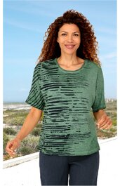 Grünes Damen-T-Shirt mit schwarz gestreiftem Muster, kurzer Arm, Rundhalsausschnitt, gerade geschnitten, getragen von stehender Frau vor Strandkulisse