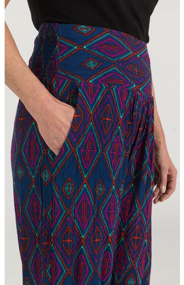 Langer Rock in Dunkelblau mit buntem geometrischem Muster aus Rauten und Linien, hoher breiter Bund, seitliche Eingrifftasche, getragen von stehender Person