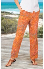 Orangene Damenhose mit buntem Paisley-Muster, gerade geschnitten, ohne sichtbare Taschen, getragen von stehender Person mit weißen Oberteil und Sandalen