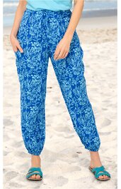 Blaue Freizeithose mit weißem Blumenmuster, elastischer Bund, gesmokte Saumabschlüsse, lässige Passform, getragen von stehendem Modell am Strand