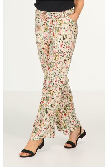 Locker sitzende Hose in Beige mit buntem abstraktem Muster, gerader Schnitt, zwei seitliche Taschen, getragen von stehender Person mit schwarzen Sandaletten