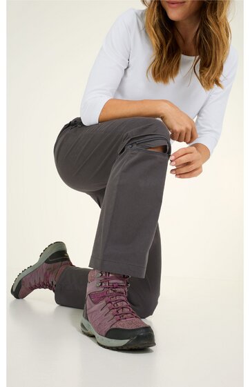 Damenhose in dunkelgrau mit Reißverschlusstasche am Oberschenkel, gerade geschnitten, kombiniert mit weißem Dreiviertelarmshirt, getragen von kniender Frau, sichtbar violette Wanderschuhe mit grauer Sohle, Outdoor-Look