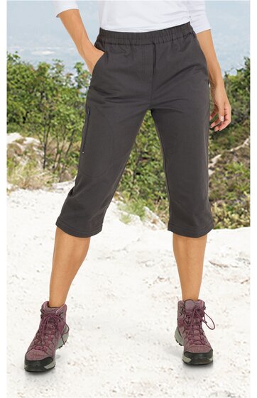 Damen-Caprihose in dunklem Grau, gerade geschnitten, elastischer Bund, seitliche Eingrifftaschen, knielang, getragen von stehender Frau im Freien, sportlich