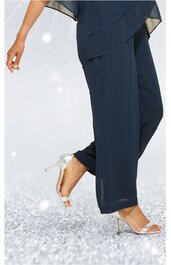 Dunkelblaue, weite Damenhose mit geradem Bein, getragen von stehender Person, kombiniert mit silberfarbenen, offenen High-Heel Sandalen mit dünnen Riemen