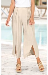 Helle, beige Damenhose mit weitem Bein, vorderen Schlitz bis zur Wade, hoher Bund mit Bundfalten, leicht gekürzte Länge, getragen von stehender Person mit weißen Oberteil und beigen Sandalen