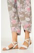 Beige Caprihose mit rosa und weißen Blumenmuster, gerade geschnitten, endet knapp oberhalb der Knöchel, getragen von stehender Person, weiße flache Sandalen mit Kreuzriemen und Knöchelriemen