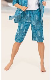 Knielange Caprihose in türkis mit abstraktem Muster, elastischer Bund, geschnitten locker, getragen von stehender Person mit leicht gespreizten Beinen