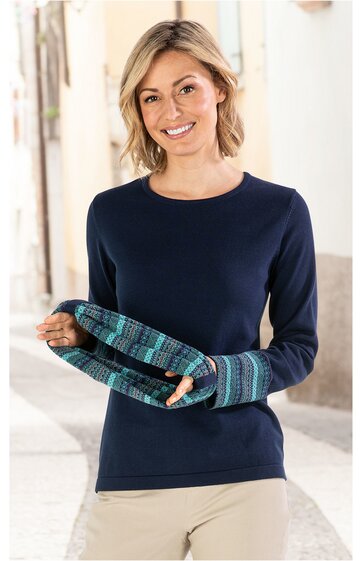 Marineblaues Langarmshirt mit Rundhalsausschnitt, schlicht, getragen von lächelnder Frau, dazu helle Hose, Frau hält blaugrün gemusterten Schal mit gestreiftem Design in den Händen