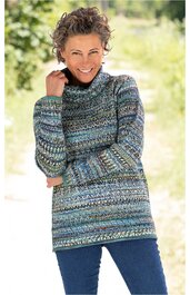 Langärmliger Rollkragenpullover mit buntem Muster in Blau- und Grüntönen, gerade geschnitten, getragen von lächelnder Frau mit braunen lockigen Haaren, stehende Pose, entspannte Armhaltung