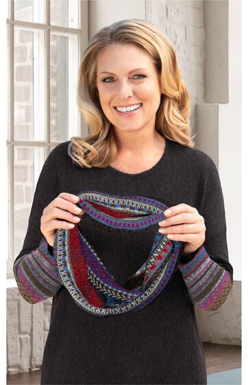 Schwarzes Langarmshirt, rundhals, Ärmel mit mehrfarbigen, gestreiften Bündchen, gehalten von stehender Frau mit blondem, schulterlangem Haar, trägt mehrfarbigen Rundschal mit Muster in Rot, Blau, Lila, Grau